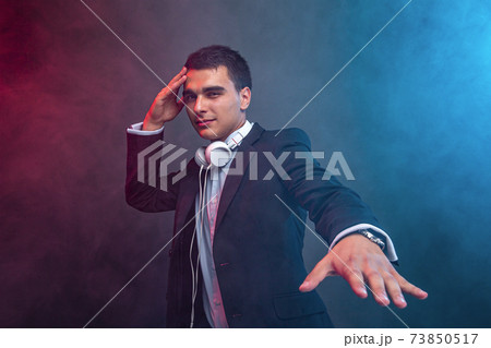 Portrait of man with headphones on dark background with smoke. Studio shoot 73850517