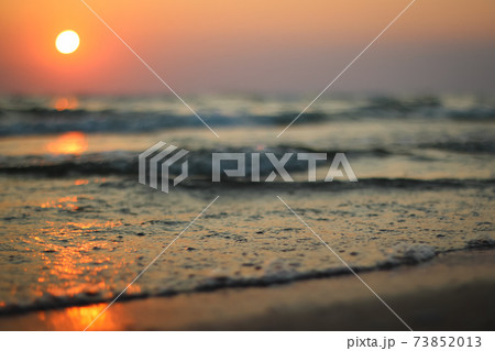 Wet sea sand on beach against background beautiful golden sunset. Close up sea sand on shore ocean during sunset.Landscape sunset sea coast. Golden wet sand sand on beach on a sunset background.  73852013