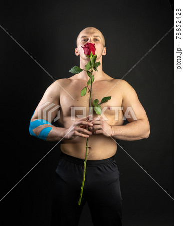 Athletic man holding a red rose, naked for the day of velentin pumped up, on his arm a teip of a bodybuilder romantic. lover guy LGBT. In the studio on a black background Cheerful smiling at the Athletic man holding a red rose, naked for the day of velentin pumped up, on his arm a teip of a bodybuilder romantic. lover guy LGBT. In the studio on a black background Cheerful smiling at the 73852423