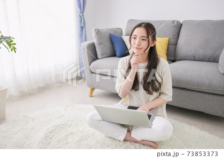 リビングでパソコンを使う若い女性 リビングでパソコンを使う若い女性 73853373