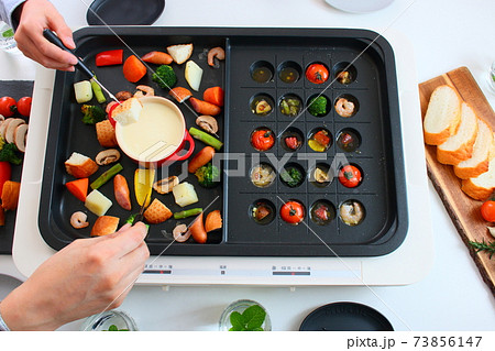ホットプレートでアヒージョとチーズフォンデュをする家族の食卓風景 ホットプレートでアヒージョとチーズフォンデュをする家族の食卓風景 73856147