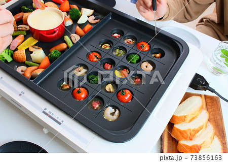 ホットプレートでアヒージョとチーズフォンデュをする家族の食卓風景 ホットプレートでアヒージョとチーズフォンデュをする家族の食卓風景 73856163