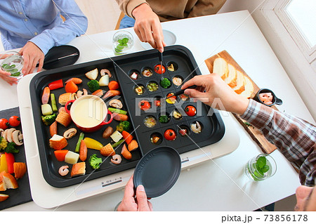 ホットプレートでアヒージョとチーズフォンデュをする家族の食卓風景 ホットプレートでアヒージョとチーズフォンデュをする家族の食卓風景 73856178