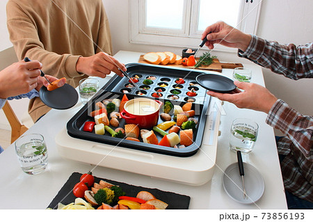 ホットプレートでアヒージョとチーズフォンデュをする家族の食卓風景 ホットプレートでアヒージョとチーズフォンデュをする家族の食卓風景 73856193