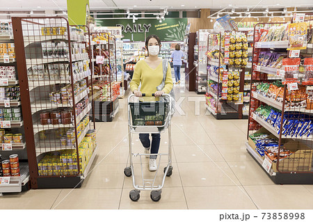 スーパーで買い物をするマスク姿の若い女性客 73858998