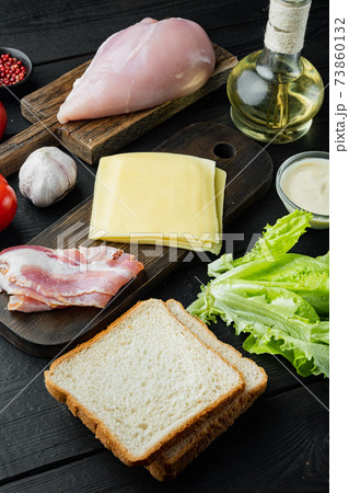Ingredient for sandwich, bacon, cheese, tomato, chicken meat, lettuce, sauce, on black wooden background 73860132