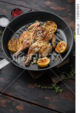 Spatchcocked poussins with chimichurri sauce, on old wooden table with copy space for text 73860464