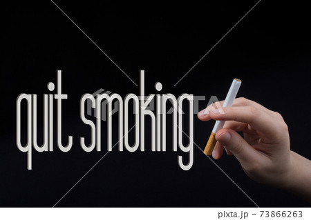 Hand is holding a cigarette on black background Hand is holding a cigarette on black background 73866263