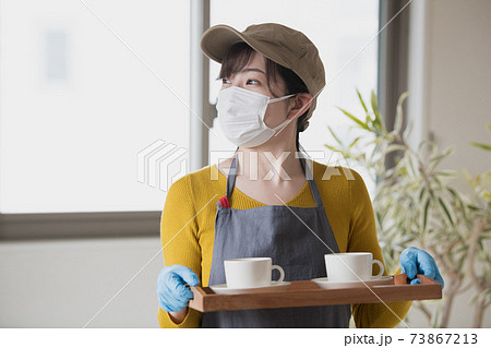 マスクと手袋をつけて接客するカフェ店員 接客業イメージの写真素材
