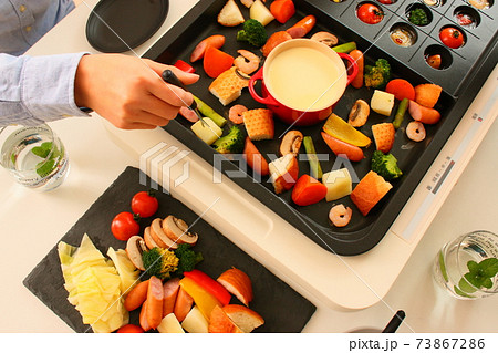 ホットプレートでアヒージョととチーズフォンデュをする家族の晩ご飯風景 73867286