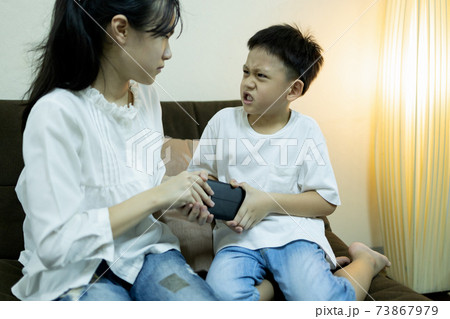 Asian sister and little brother fighting for smartphone,aggressive kid boy trying to grab a phone from child girl,two children quarreling, arguing for playing with phone,online game addiction problems 73867979