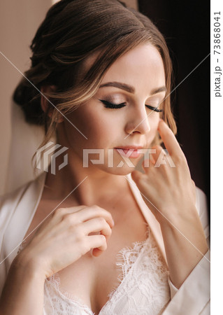 Portrait of attractive young bride in negligee. Beautiful woman stand by window 73868041