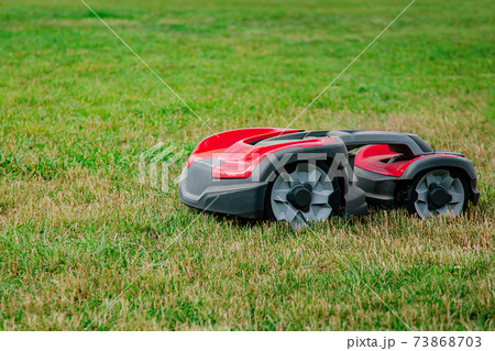 Robotic lawn mower on grass, side view. Garden modern remote technology. Robotic lawn mower on grass, side view. Garden modern remote technology. 73868703