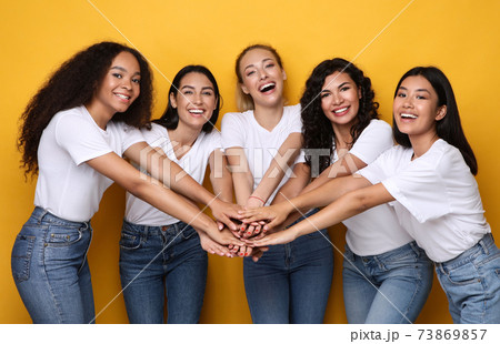 Five Happy Multiethnic Women Holding Hands Posing On Yellow Background 73869857
