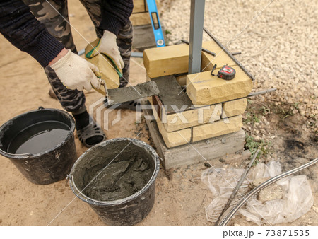 The worker is laying bricks on the fence The worker is laying bricks on the fence 73871535