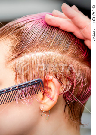 Hairdresser makes short pink hairstyle 73876445