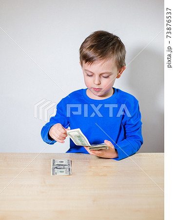 Happy child with money dollar, little businessman. Pile of United States dollar hundred USD banknotes Happy child with money dollar, little businessman. Pile of United States dollar hundred USD banknotes 73876537
