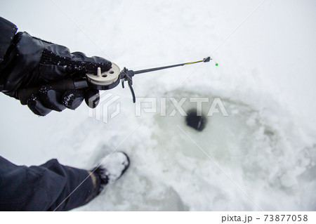 Close up of a ricky fisherman with a fishing rod. Ice and fishing rod for winter fishing. Winter fishing. Small catch of fish. 73877058