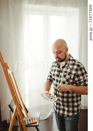 Artist at work. Young man doing easel drawing 73877806