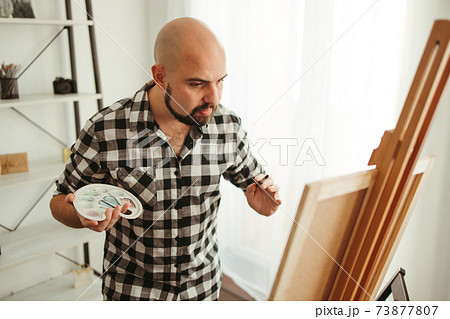 Artist at work. Young man doing easel drawing 73877807