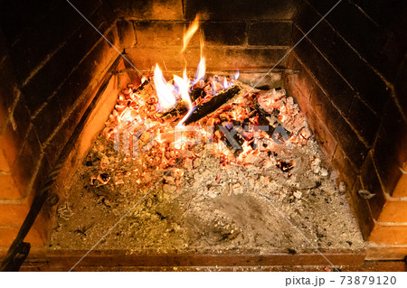 smoldering firewood and ash in home fireplace 73879120