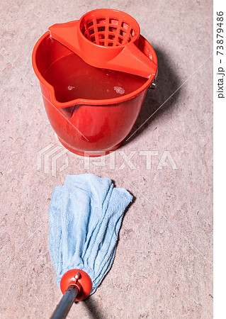 mop cleans linoleum floor near red bucket 73879486