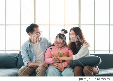 Happy asian family sitting on sofa and playing dolls with their daughter down syndrome child in living room at morning time, Activity happy family lifestyle concept, 73879979