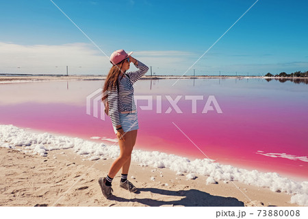 Young smiling woman tourist with long hair near saline pink lake. 73880008