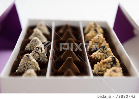 In the box are rows of different chocolates. A gift or greeting. Festive dessert. 73880742