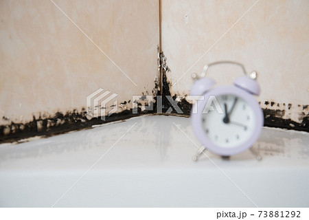 There's a clock in the shower stall. On the background of silicone putty, black from mold. The concept of old age and the passage of time. Control of the time of application of the mold control agent There's a clock in the shower stall. On the background of silicone putty, black from mold. The concept of old age and the passage of time. Control of the time of application of the mold control agent 73881292