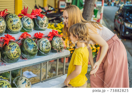 Mom and son tourists look at Watermelons with festive engraving on Tet Eve. Tet is Lunar New Year and celebrated during four days in Vietnam Mom and son tourists look at Watermelons with festive engraving on Tet Eve. Tet is Lunar New Year and celebrated during four days in Vietnam 73882825