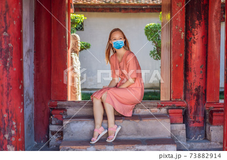 Woman tourist wearing a medical mask during COVID-19 coronavirus in Temple of Literature in Hanoi in Southeast Asia, Vietnam. Temple of Confucius in Vietnamese capital. Vietnam reopens after Woman tourist wearing a medical mask during COVID-19 coronavirus in Temple of Literature in Hanoi in Southeast Asia, Vietnam. Temple of Confucius in Vietnamese capital. Vietnam reopens after 73882914
