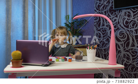 Child girl schoolgirl enthusiastically drawing with brushes and paints, distance education at home 73882922