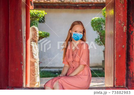 Woman tourist wearing a medical mask during COVID-19 coronavirus in Temple of Literature in Hanoi in Southeast Asia, Vietnam. Temple of Confucius in Vietnamese capital. Vietnam reopens after Woman tourist wearing a medical mask during COVID-19 coronavirus in Temple of Literature in Hanoi in Southeast Asia, Vietnam. Temple of Confucius in Vietnamese capital. Vietnam reopens after 73882983