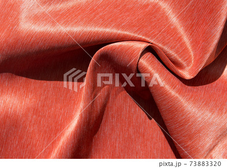 Luxurious expensive orange fabric as an elegant background with beautiful tints of light. Soft folds fall and create light waves 73883320