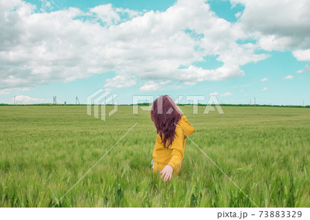 Beautiful girl with bright red hair is happy in a wheat field. Blue sky with small cloudless clouds, agriculture and village concept 73883329