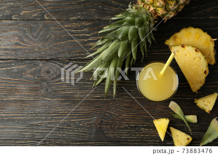 Ripe pineapple and glass of juice on wooden background 73883476