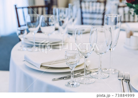 Fancy table set for dinner with napkin glasses in restaurant, luxury interior background. Wedding elegant banquet decoration and items for food arranged by catering service on white tablecloth table. 73884999