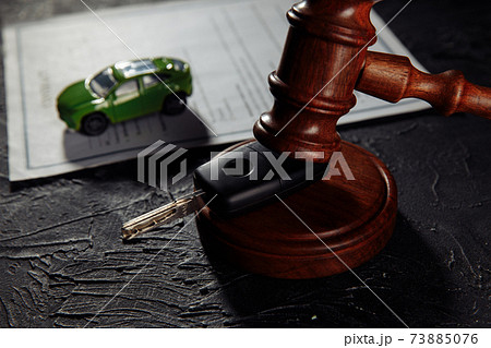 Wooden hammer and toy car with car keys. Insurance, court case close-up 73885076