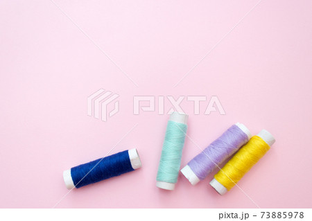 Colored sewing thread on a pink background 73885978