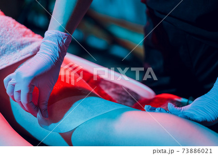 Mid section of therapist waxing woman's leg at spa center. Mid section of therapist waxing woman's leg at spa center. 73886021