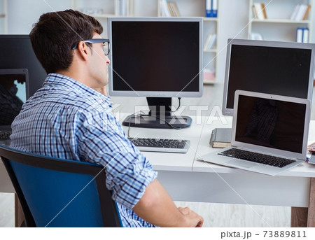 Businessman sitting in front of many screens Businessman sitting in front of many screens 73889811