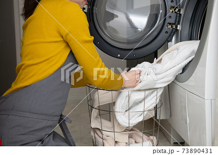 ドラム式洗濯乾燥機に洗濯物を出す 入れる女性の手元の写真素材