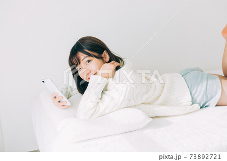 ベッドに寝転がってスマホを見る女の子 ベッドに寝転がってスマホを見る女の子 73892721