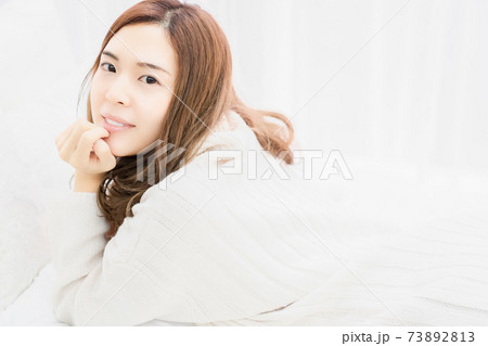 ベッドに肘をついて横になる若い女性 ベッドに肘をついて横になる若い女性 73892813