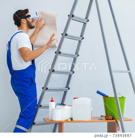 Man with VR glasses gluing wallpaper 73893687