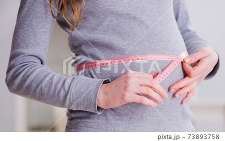 Pregnant woman measuring belly with centimeter Pregnant woman measuring belly with centimeter 73893758