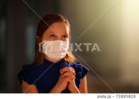 Girl in face mask praying for coronavirus victim Girl in face mask praying for coronavirus victim 73895829