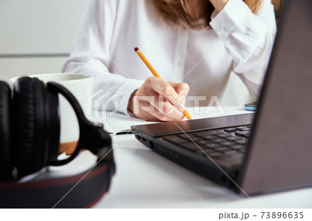 Remote work. Woman makes notes in notebook and using laptop for study. Distance education and e learning concept Remote work. Woman makes notes in notebook and using laptop for study. Distance education and e learning concept 73896635