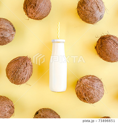 Pattern, texture with coconuts and coconut milk, cocktail on yellow background. Tropical abstract background. Flat lay, top view. 73896651